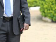 man in black suit jacket holding briefcase